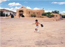  ?? JOURNAL FILE ?? A young boy plays ball in front of the San Tomas Catholic Church in Abiquiú. According to oral history, and now DNA, several families in the area are descendant­s of Native Americans who were brought to the area as captives of the Spanish.