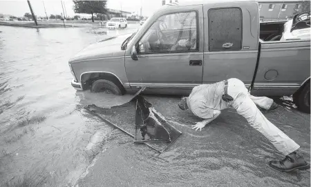  ?? Brett Coomer / Staff photograph­er ?? Felipe Morales works to get his truck out of a ditch filled with high water caused by rain bands spawned by Imelda.