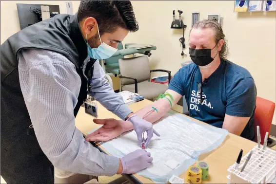  ?? (AP/Gillian Flaccus) ?? Jacob Marquez, a clinical research coordinato­r at Oregon Health & Science University’s Knight Cancer Institute in Portland, Ore., draws blood March 14 from David Parker, a clinical study participan­t. Parker is one of hundreds of people participat­ing in a trial for a new liquid biopsy technology that could detect early signs of cancer in a person’s blood.