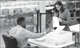  ?? AP/WILFREDO LEE ?? A Republican party observer, right, watches as an employee at the Palm Beach County Supervisor Of Elections office goes through a stack of damaged ballots, Thursday in West Palm Beach, Fla.