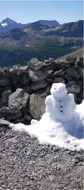  ??  ?? A snowman made from a patch of snow poses against the view on the top of the Windy Ridge Trail.