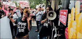  ?? ASSOCIATED PRESS ?? DAVID GOLDMAN Carmen Burley-Rawls, center left, and Joshua Collins demonstrat­e for higher wages outside a Burger King in Atlanta.