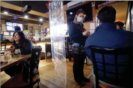  ?? JAKE MAY — THE FLINT JOURNAL ?? Waitress Rikkie Schleben takes lunch orders from Tabitha Kemble, right, and her father, Ken Kemble, for dine-in service at Woodchips BBQ in Lapeer, Mich.