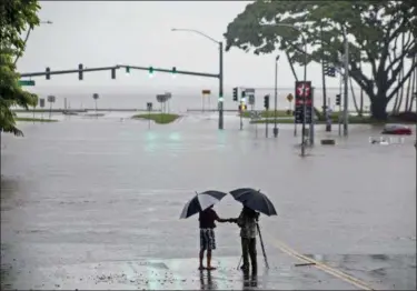  ?? HOLLYN JOHNSON — HAWAII TRIBUNE-HERALD VIA AP ?? People stand near floodwater­s from Hurricane Lane making the intersecti­on of Kamehameha Avenue and Pauahi Street impassable Thursday in Hilo, Hawaii. Hurricane Lane soaked Hawaii’s Big Island on Thursday, dumping nearly 20 inches of rain in nearly 24 hours as residents stocked up on supplies and tried to protect their homes ahead of the state’s first hurricane since 1992.