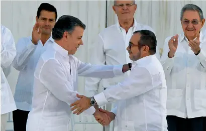  ?? AFP ?? Colombian President Juan Manuel Santos and the head of the Farc guerrilla Timoleon Jimenez, aka Timochenko, shake hands during the signing of the historic peace agreement in Cartagena, Colombia, on Tuesday. —