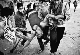  ?? AHMED JADALLAH/REUTERS PHOTO ?? Protesters opposed to the decree issued last week by President Mohammed Morsi carry away a wounded man during clashes with police Tuesday in Cairo’s Tahrir Square. The nationwide protests, which drew tens of thousands, have resulted in at least four...