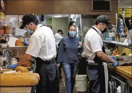  ?? Irfan Khan Los Angeles Times ?? EMPLOYEES work at Langer’s Deli on Tuesday. Under new state rules, workers in most cases can shed their masks if they are fully vaccinated against COVID-19.