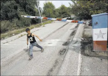  ?? DARKO VOJINOVIC/THE ASSOCIATED PRESS ?? A migrant child walks at the “Horgos 2” border crossing that leads into Hungary, from Horgos, Serbia, with the old Yugoslav communist flag on the abandoned border point on Sept. 17, 2015. Europe’s open borders are looked at differentl­y these days,...