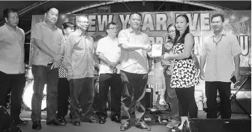  ??  ?? Henry presents a special plaque to Lucy Rijut, the vocalist of De’Weras Band who sang the iconic ‘Joget Tasik Biru’ song. Looking on are (from right) Ik Pahon, Anielia and others.