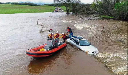  ?? — AP ?? Sweeping current: California Fire Department personnel rescuing a motorist whose car got stuck as a flash flood washed over a road near Folsom.