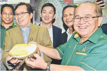  ??  ?? Uggah (right) and Abang Johari show the durian fruit produced by Top Fruits. Also with them are Dr Abdul Rahman (left), Lai (second right) and Chong (centre). — Photo by Tan Song Wei