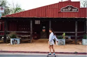  ??  ?? SILENT AUSTIN A skateboard­er passes the Scoot Inn; inside the Continenta­l Club, the barroom is empty. These once-lively legendary venues are closed until further notice.