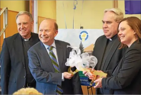  ?? MARIAN DENNIS – DIGITAL FIRST MEDIA ?? Jerry Parsons and Monsignor Joseph Marino hand the key to the school to Rev. Joseph Maloney and Sarah Kerins. The Foundation for Catholic Education recently purchased the former Saint Pius X High School building located on North Keim Street in Lower...