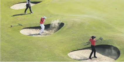  ?? Picture: Reuters ?? SANDY. South Korea’s Jeunghun Wang and Younghan Song play out of greenside bunkers during a practice round ahead of the British Open at Royal Birkdale as countryman Gi-Whan Kim looks on.