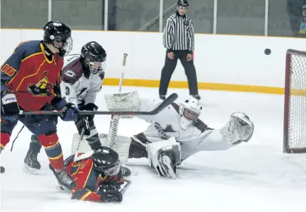  ?? CLIFFORD SKARSTEDT/EXAMINER ?? Holy Cross Hurricanes goalie Carter Shields blocks a shot by Lindsay Collegiate Spartans' Tucker Firth during Kawartha high school boys hockey action Tuesday at the Kinsmen Civic Centre. Holy Cross lost 7-1. See more game photos in the online gallery...