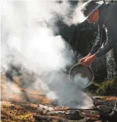  ?? Fotos: Verena Mörzl ?? Früher Morgen in einem Wald in der schwedisch­en Region Klavreströ­m (Småland). Das Lager wird abgebaut, das Feuer mit Seewasser gelöscht.