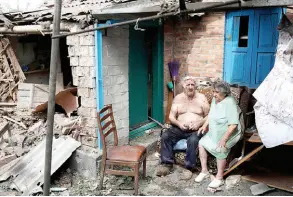  ?? ?? A wounded man and his wife sit in the yard of their heavily damaged house following a rocket a ack in the town of Bakhmut, Donetsk region.