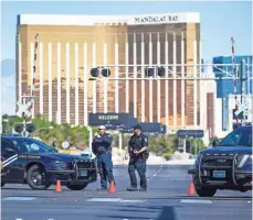  ?? TOM TINGLE, THE ARIZONA REPUBLIC ?? Police stand at a roadblock on Las Vegas Boulevard at Sunset Road near the Mandalay Bay on Monday morning, the day after scores of people were fatally shot.