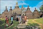  ??  ?? Women walk toward a temple in Myanmar.