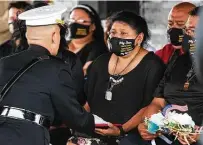  ??  ?? Espinoza’s mother, Elizabeth Holguin, is presented with his Purple Heart on Monday at the city cemetery in Laredo.