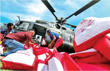  ?? — Reuters photo ?? Villagers affected by the earthquake unload aid delivered by an Indonesian military helicopter in Lindu village south of Palu.