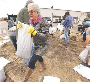  ?? Al Seib Los Angeles Times ?? MONTECITO resident Terri Eddy gets sandbags to protect her home below the Thomas fire burn area.