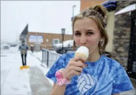  ?? ASSOCIATED PRESS ?? Westmont High School student enjoys a free ice cream cone from the Westmont Dairy Queen location in Johnstown, Pa. as snow falls on the first day of spring, Tuesday. The Dairy Queen Corp. was giving out one free cone per customer to celebrate the first...