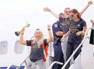  ?? KATHY WILLENS/ ASSOCIATED PRESS ?? Julie Ertz, left, Megan Rapinoe, top center, and Alex Morgan, top right, celebrate after arriving at Newark Liberty Internatio­nal Airport with the rest of the United States soccer team Monday.