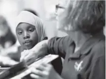  ??  ?? Student Megeney Ali, 7, listens to instructio­n from Mary Ann Bash, the creator and director of the Denver Public Schools Foundation program Each One Teach One.