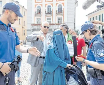  ??  ?? Die Polizei in Locarno ermahnt eine Frau, die aus Protest gegen das neue Gesetz ihr Gesicht verhüllt hat. Andere Kantone könnten dem Tessiner Anti-Burka-Gesetz bald folgen.