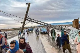  ?? Habib Ullah/Associated Press ?? People pass by a damaged electric pole caused by flooding due to heavy rains on Thursday near Chaman area, Pakistan. Glacier melting has caused a new flood alert.