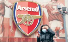  ?? REUTERS ?? A woman wearing a mask walks past Arsenal’s Emirates Stadium on Friday.