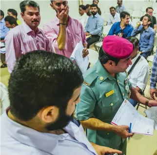  ??  ?? A GDRFA officer assists amnesty-seekers with their papers on the first day of the amnesty programme at Al