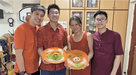  ??  ?? The 16-year-old Singaporea­n Macken Lee (right), his mother Janice Yeo, founder of the “Uku Angels,” a community volunteer group in the Biyun Internatio­nal Community, and family members with their favorite New Year dish Lo Hei. — All photos by Ti Gong