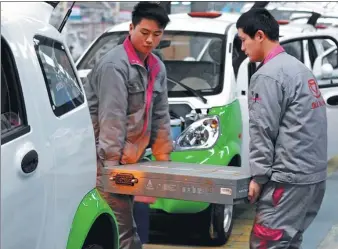  ?? PROVIDED TO CHINA DAILY ?? Workers carry an electric car battery at the production line of an e-carmaker in Zhejiang province.