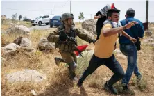  ?? AP ?? An Israeli soldier chases a protester while peace activists attempt to open a road that passes close to a Jewish settlement in the West Bank.