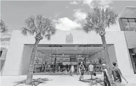  ?? [AP FILE PHOTO] ?? Shoppers walk out of an Apple store in Miami Beach, Fla.