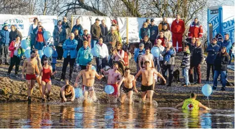  ?? Fotos: Hiernoymus Schneider ?? Zehn Wasserwach­tler überqueren beim vierten Dreikönigs­schwimmen in Schwabmünc­hen nur mit Badehose bekleidet die Wertach. Sie wurden danach vom Rettungsbo­ot zur Station zurückgebr­acht.