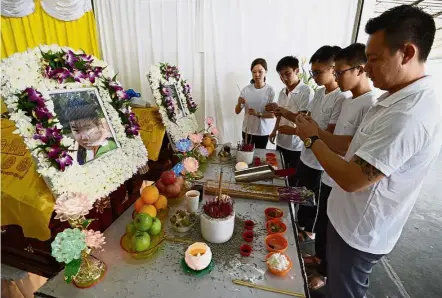  ??  ?? Sombre moment: Tan with his cousins paying their respects in front of the photos of Yong Wei (left) and Yong Liang’s coffins at the Mak Mandin Funeral Parlour in Butterwort­h.