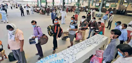  ??  ?? MIGRANT LABOURERS their native villages.
who arrived in Prayagraj, Uttar Pradesh, from Gujarat by a special train wait to leave for