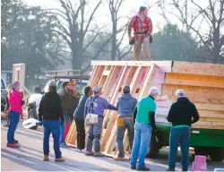  ?? Ricardo Brazziell/Austin American-Statesman via AP ?? ■ Volunteers and Habitat for Humanity workers cooperate to build the framing for their first “net zero” home for Steve and Elida Quiroz on Feb. 8 in East Austin, Texas. The “net zero” homes have solar panels and energy-efficient features that will mean...