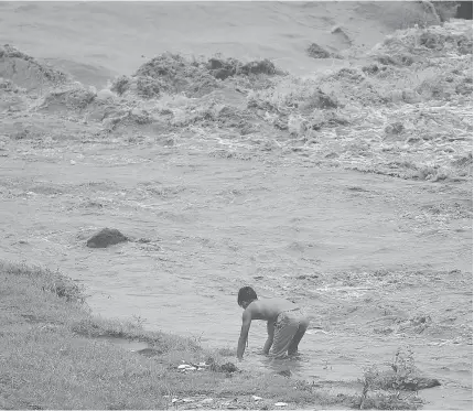  ??  ?? A resident tries to catch fish along a river near Mayon Volcano in Daraga town, Albay province, south of Manila on January 27. Millions of tons of ash and rocks from an erupting Mayon Volcano are threatning to bury surroundin­g communitie­s because of...