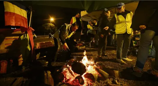  ?? (Photos S. Botella) ?? Chaque soir, ils sont des dizaines de «gilets jaunes» à se relayer. Certains dorment sur place pour ne pas laisser le campement sans surveillan­ce.