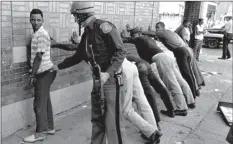  ?? AP PHOTO ?? In this July 24, 1967, file photo, a Michigan State police officer searches a youth on Detroit’s 12th Street where looting was still in progress after the previous day’s rioting.