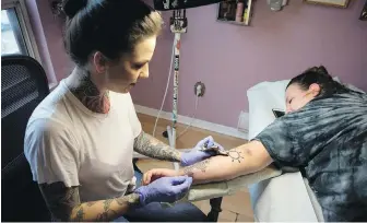  ?? CHRIS YOUNG, THE CANADIAN PRESS ?? Tattoo artist Lizzie Renaud removes Hedley tattoo from Sabrina Johnston’s arm.