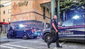  ?? JOHN SPINK/JOHN.SPINK@AJC.COM ?? Atlanta police accompanie­d an officer Thursday morning to Grady Memorial Hospital after he was wounded in a shooting on Marietta Street in the West Midtown shopping district. The four-year department veteran’s name was not released.