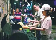  ?? A YUAN / FOR CHINA DAILY ?? Tourists barbeque and make pizza in the open air kitchen of a B&B called Prodigy Outdoor Base in Moganshan of Zhejiang province.