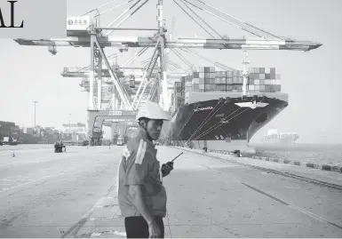  ?? STR / AFP / GETTY IMAGES FILES ?? A worker looks on as a cargo ship is loaded at a port in Qingdao, China, in July 2017. Canada will pursue a deeper trading relationsh­ip with China, Prime Minister Justin Trudeau said on Tuesday despite a clause in the USMCA that places restrictio­ns on free-trade agreements with “non-market” countries.