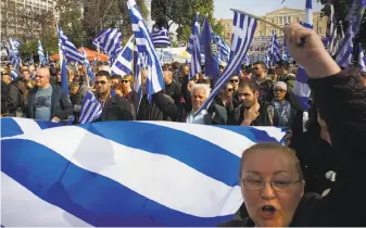  ?? Milos Bicanski / Getty Images ?? Demonstrat­ors wave Greek national flags during a protest in Athens. Greeks argue that use of the name Macedonia implies territoria­l claims on its own province of the same name.