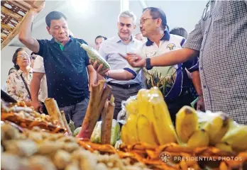  ?? RENE LUMAWAG/PRESIDENTI­AL PHOTO ?? President Rodrigo R. Duterte listens to Agricultur­e Secretary Emmanuel Piñol as the latter shows a product from one of the Tienda Farmers and Fisherfolk­s Outlets during the launching of the Department of Agricultur­e's partnershi­p with Ayala Malls at...